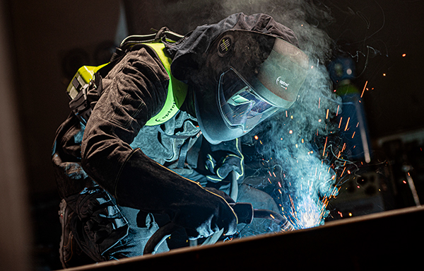 Arbeiter mit vollständiger Schutzausrüstung beim professionellen Schweissen